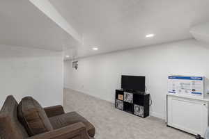 Living area featuring a textured ceiling and light colored carpet