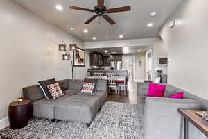 Living room featuring ceiling fan and dark wood-type flooring