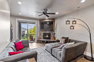 Living room with a fireplace, light wood-type flooring, and ceiling fan