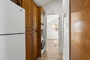 Clothes washing area with light vinyl plank flooring and washer / dryer