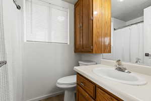 Bathroom featuring vanity, a textured ceiling, toilet, and storage space