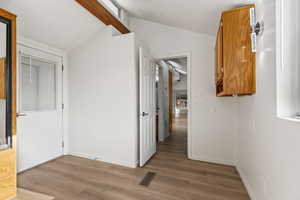 Master bedroom featuring light vinyl plank flooring and lofted ceiling with beam