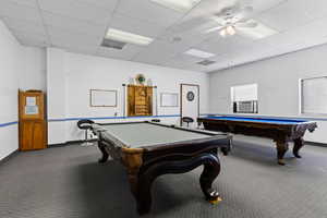 Recreation room featuring a paneled ceiling, ceiling fan, dark colored carpet, and pool table