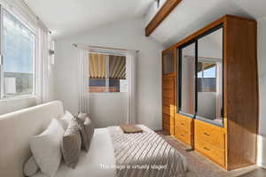 Bedroom featuring multiple windows and lofted ceiling