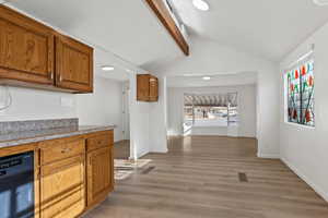 Kitchen featuring black dishwasher, lofted ceiling with beam, a wealth of natural light, and light vinyl plank floors