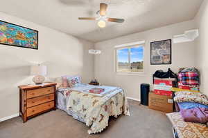 Carpeted bedroom with ceiling fan and a textured ceiling