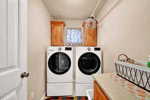 Washroom featuring cabinets, a textured ceiling, and washer and clothes dryer