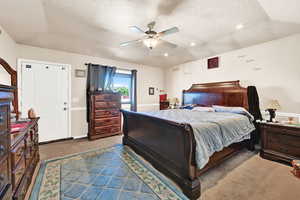 Carpeted bedroom featuring a textured ceiling and ceiling fan