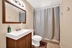 Bathroom with a shower with curtain, vanity, and toilet