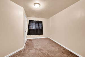 Carpeted spare room featuring a textured ceiling