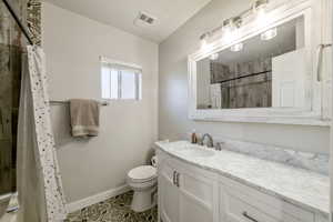 Bathroom featuring tile patterned flooring, a shower with curtain, vanity, and toilet