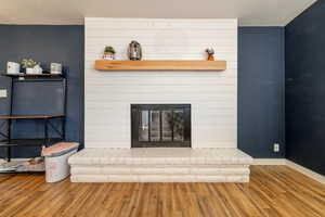 Living room with hardwood / wood-style floors, a large fireplace, and a textured ceiling