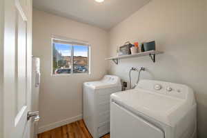 Laundry room with washer and clothes dryer and dark hardwood / wood-style flooring