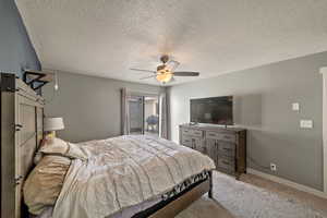 Carpeted bedroom featuring a textured ceiling and ceiling fan