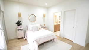 Bedroom with light hardwood / wood-style floors and ensuite bathroom