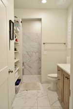 Bathroom with a tile shower, vanity, and toilet