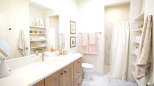 Bathroom with vanity, curtained shower, and toilet