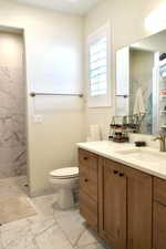 Bathroom with vanity, toilet, and tiled shower