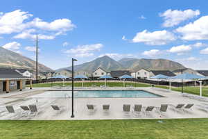 View of pool with a patio area, a mountain view, and a yard