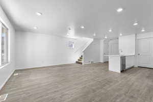 Unfurnished living room with sink, laminate flooring, and a textured ceiling