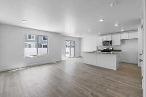 Kitchen featuring white cabinets, a center island with sink, sink, light hardwood / wood-style flooring, and appliances with stainless steel finishes