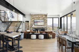 Dining space featuring a stone fireplace, a wealth of natural light, light hardwood / wood-style flooring, and a chandelier