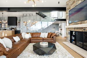 Living room with a stone fireplace, a chandelier, and wood-type flooring