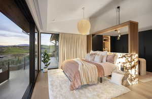 Bedroom featuring access to exterior, wood-type flooring, and lofted ceiling