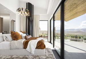 Bedroom featuring access to exterior, a mountain view, multiple windows, and an inviting chandelier