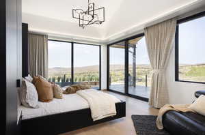 Bedroom with access to exterior, vaulted ceiling, light hardwood / wood-style flooring, a mountain view, and a chandelier