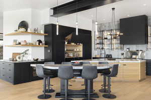 Kitchen featuring a kitchen breakfast bar, decorative backsplash, a center island, and light wood-type flooring