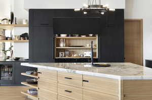 Bar featuring light stone countertops, wine cooler, light hardwood / wood-style flooring, and hanging light fixtures