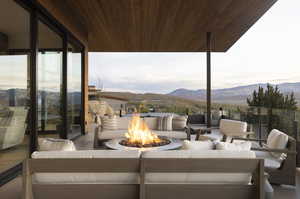 View of patio with a mountain view and an outdoor living space with a fire pit