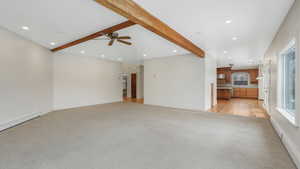 Unfurnished living room with beam ceiling, light colored carpet, a baseboard radiator, and ceiling fan