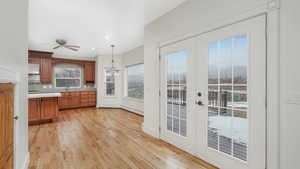 Kitchen with ceiling fan, french doors, hanging light fixtures, light hardwood / wood-style flooring, and backsplash