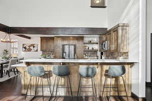 Kitchen with backsplash, dark wood-type flooring, decorative light fixtures, stainless steel appliances, and a chandelier