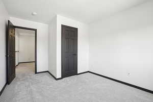 Unfurnished bedroom featuring light colored carpet and a closet