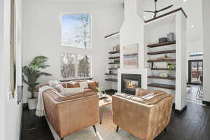 Living room with built in shelves, a towering ceiling, dark hardwood / wood-style flooring, and plenty of natural light