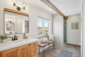 Bathroom featuring beamed ceiling, vanity, toilet, and tiled shower