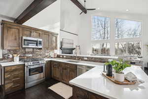 Kitchen featuring backsplash, sink, beamed ceiling, a healthy amount of sunlight, and stainless steel appliances