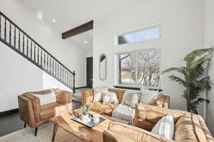 Living room with beam ceiling, a high ceiling, and light wood-type flooring