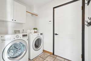 Laundry room with cabinets, light tile patterned floors, and washer and clothes dryer