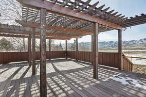 Snow covered deck featuring a pergola and a mountain view