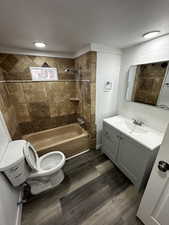 Bathroom with toilet, tub / shower combination, wood finished floors, and vanity