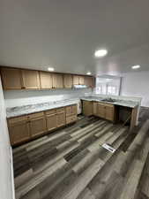 Kitchen with a peninsula, dark wood-type flooring, visible vents, and under cabinet range hood