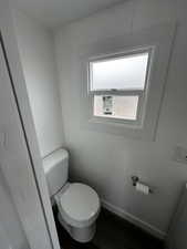 Bathroom featuring wood finished floors, toilet, and baseboards