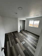 Spare room with dark wood finished floors, visible vents, and baseboards