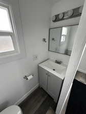 Bathroom with vanity, wood finished floors, toilet, and baseboards