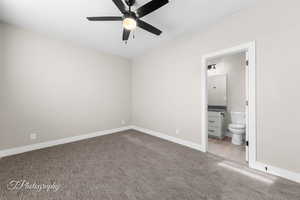 Unfurnished bedroom featuring ensuite bathroom, ceiling fan, and light colored carpet