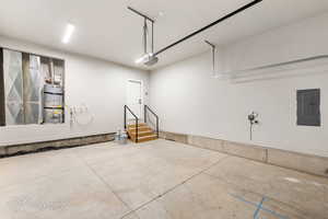 Garage with electric panel, water heater, and a garage door opener